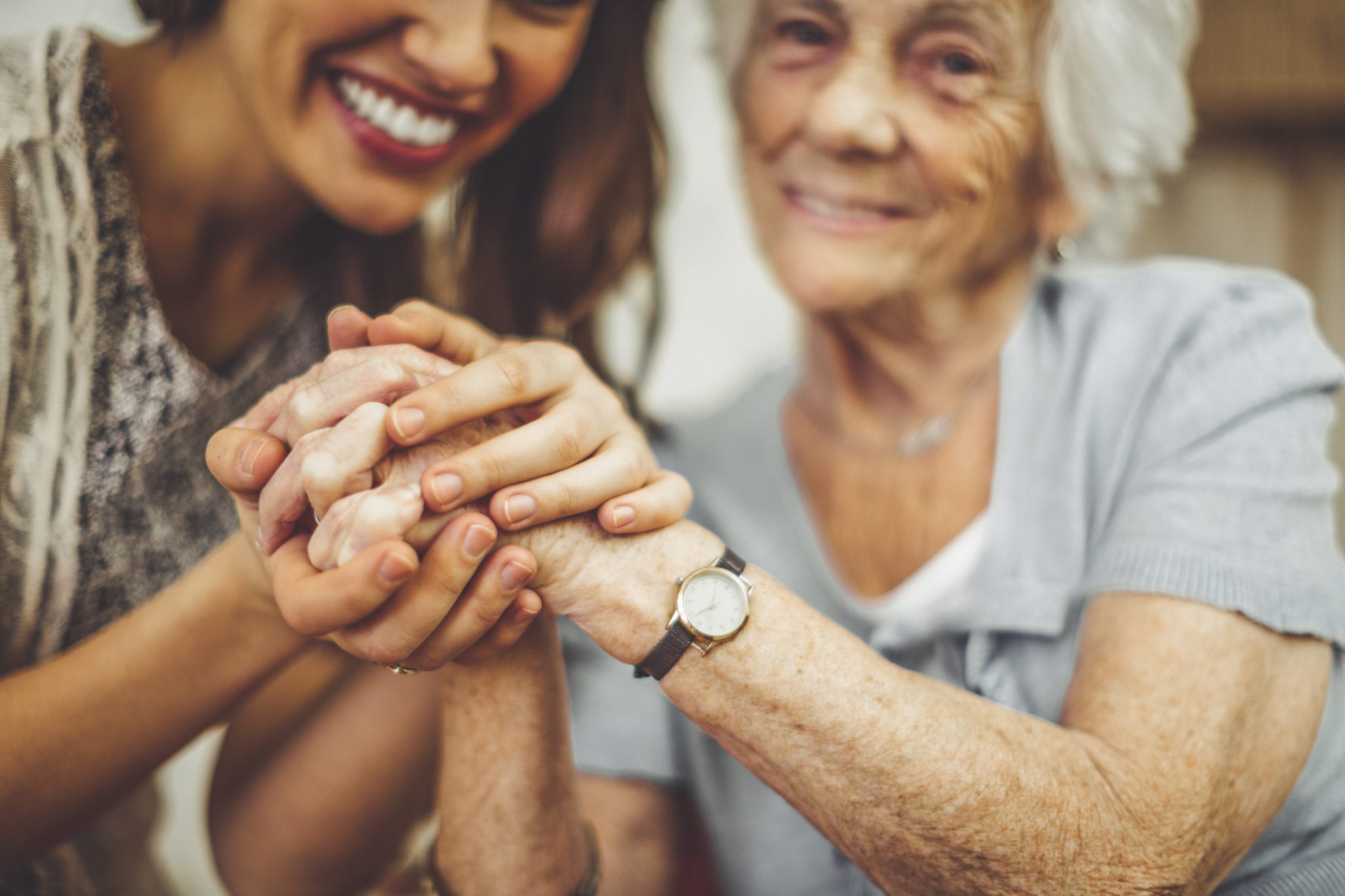 Female caregiver holding hands with elderly woman