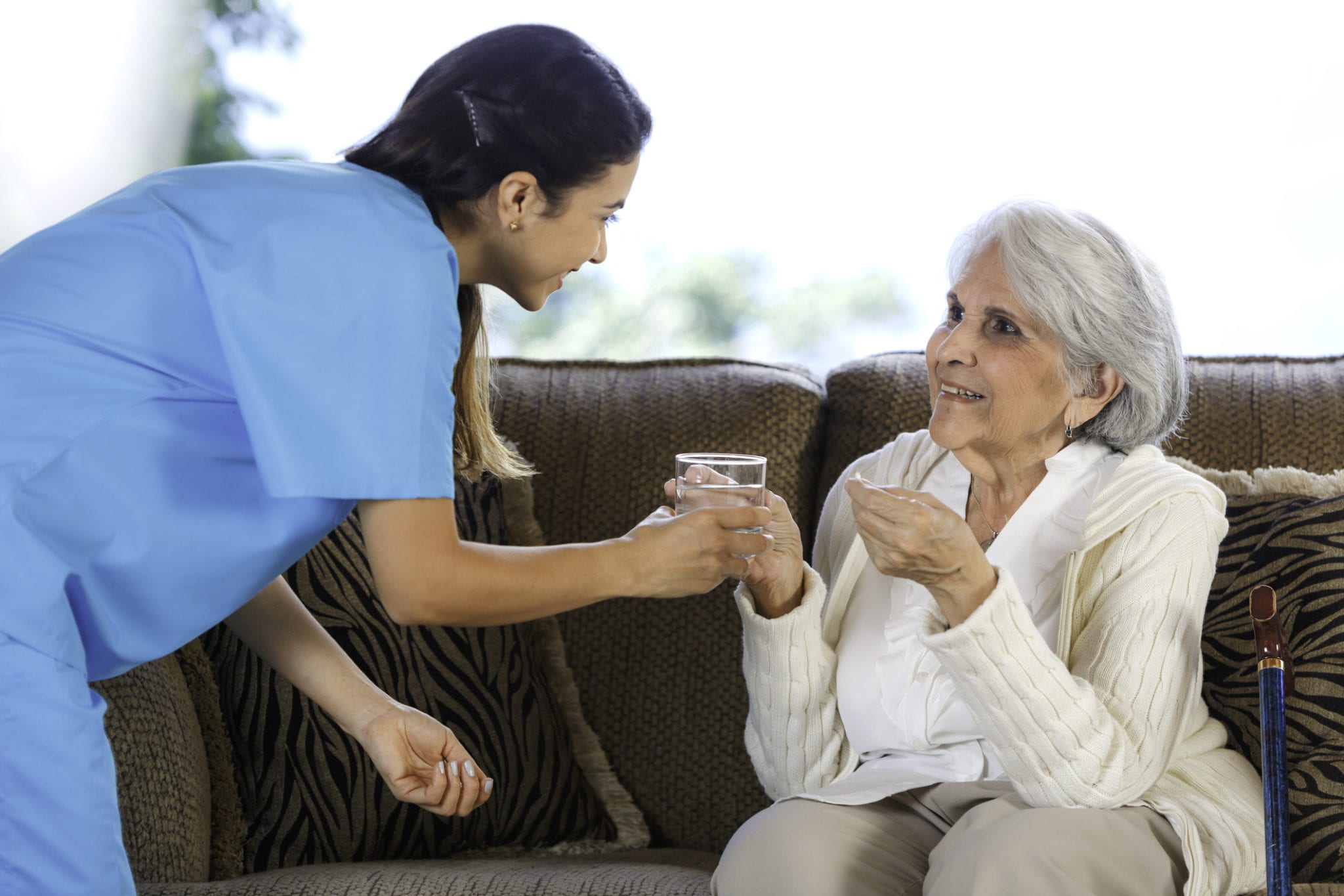 Female hospice nurse giving medication to a female patient